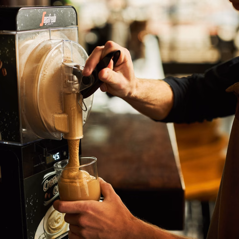 Close-Up-Imagebild Hand füllt Crema Caffè in ein Glas